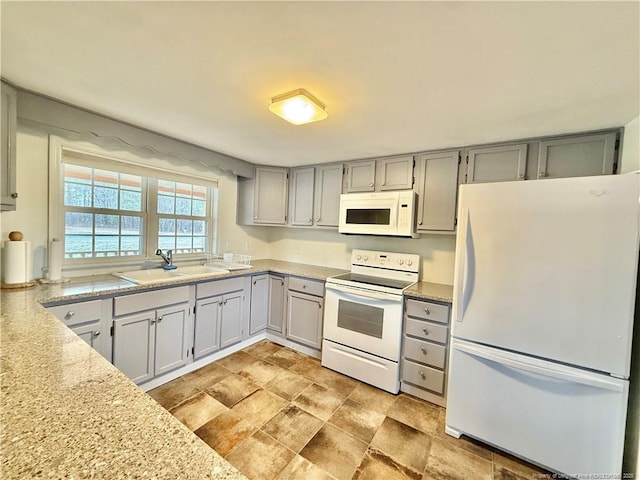 5089 Tobacco Rd, Orrum, NC 28369 - kitchen with white appliances, a sink, light countertops, gray cabinetry, and stone finish flooring