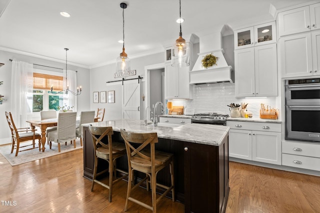 1412 Wakefield Farm Rd, Zebulon, NC 27597 - kitchen featuring appliances with stainless steel finishes, a sink, custom range hood, a center island with sink, and ornamental molding