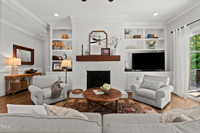 1412 Wakefield Farm Rd, Zebulon, NC 27597 - living room with a ceiling fan, crown molding, built in shelves, wood finished floors, and a fireplace