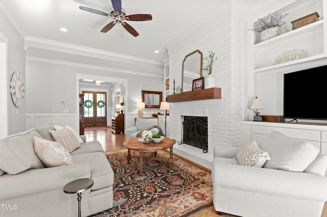 1412 Wakefield Farm Rd, Zebulon, NC 27597 - living room with crown molding, wood finished floors, ceiling fan, a fireplace, and wainscoting