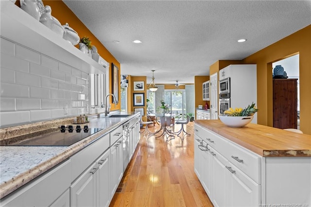 116 Fox Run Ct, West End, NC 27376 - kitchen with stainless steel appliances, a textured ceiling, a sink, white cabinetry, and light wood-type flooring