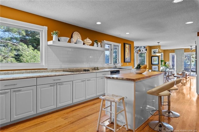 116 Fox Run Ct, West End, NC 27376 - kitchen featuring open shelves, butcher block countertops, a textured ceiling, a breakfast bar, and a sink