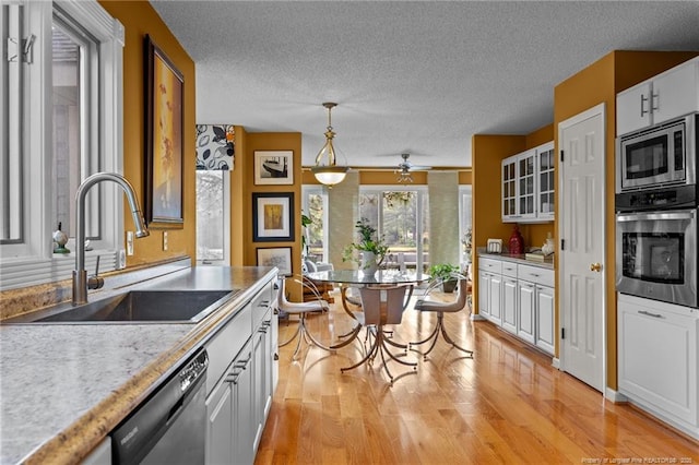 116 Fox Run Ct, West End, NC 27376 - kitchen with stainless steel appliances, a sink, light wood-style floors, a textured ceiling, and light countertops