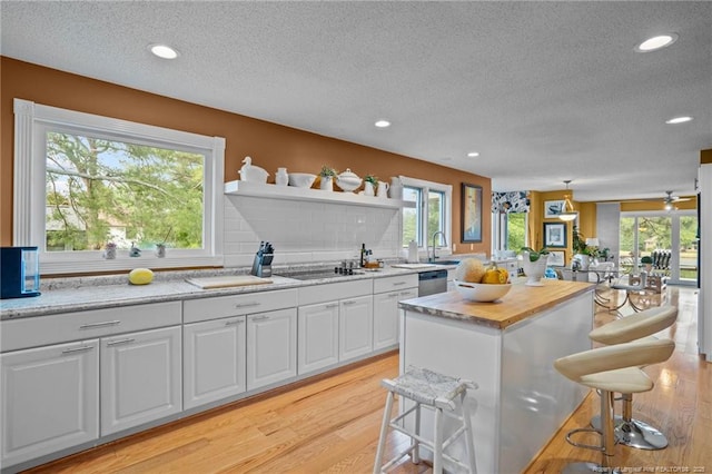 116 Fox Run Ct, West End, NC 27376 - kitchen featuring a textured ceiling, light wood-style flooring, a breakfast bar area, white cabinets, and open shelves