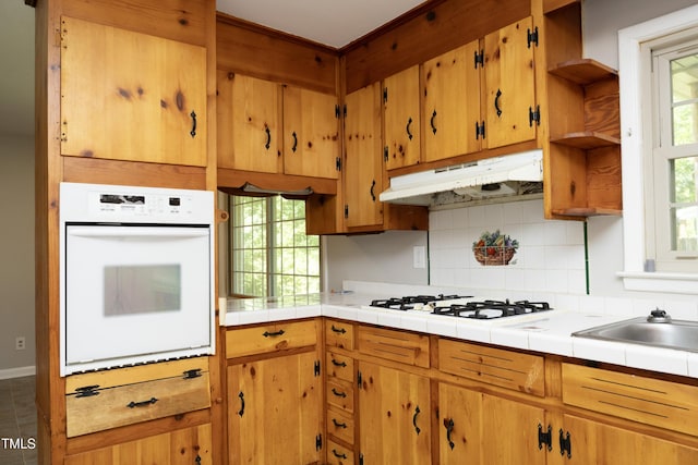 1209 Landon St, Durham, NC 27703 - kitchen with white appliances, under cabinet range hood, open shelves, tasteful backsplash, and tile counters