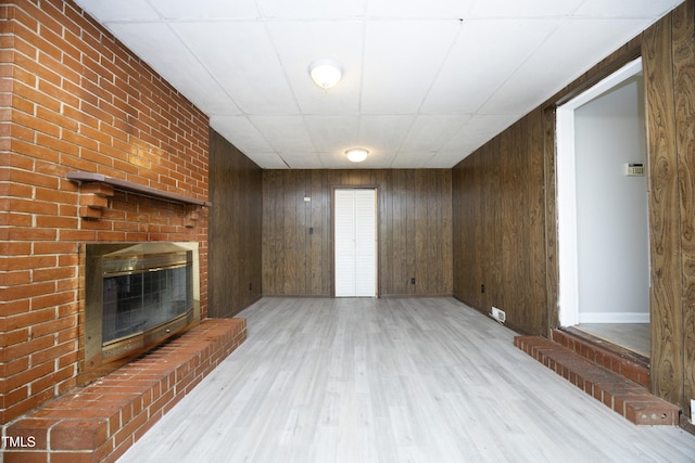 1209 Landon St, Durham, NC 27703 - unfurnished living room with a fireplace, light wood-style floors, wood walls, and baseboards