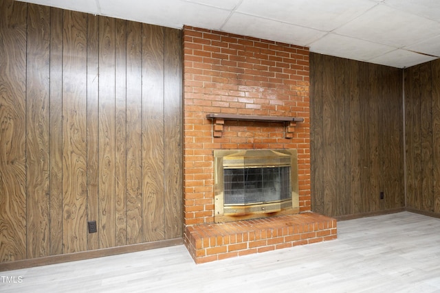 1209 Landon St, Durham, NC 27703 - unfurnished living room featuring wood walls, wood finished floors, baseboards, a brick fireplace, and a drop ceiling