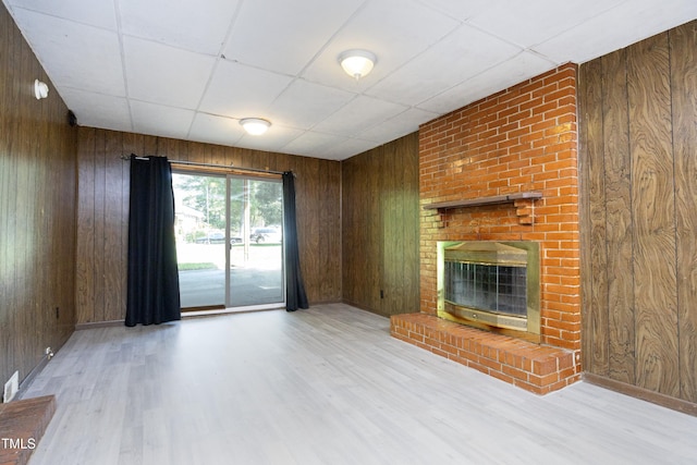 1209 Landon St, Durham, NC 27703 - unfurnished living room with wood walls, a paneled ceiling, wood finished floors, a brick fireplace, and baseboards