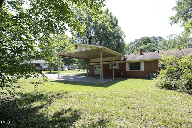 1209 Landon St, Durham, NC 27703 - rear view of property with central air condition unit, a yard, an attached carport, brick siding, and a chimney