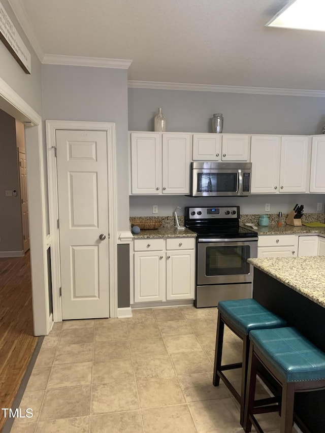 352 Riverstone Dr, Clayton, NC 27527 - kitchen with appliances with stainless steel finishes, crown molding, light stone countertops, white cabinets, and a kitchen breakfast bar