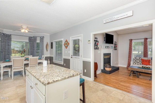 352 Riverstone Dr, Clayton, NC 27527 - kitchen featuring plenty of natural light, ornamental molding, a kitchen bar, a ceiling fan, and a center island