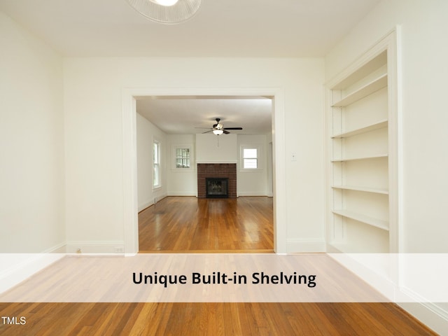 1410 Shawnee St, Durham, NC 27701 - unfurnished living room featuring wood finished floors, a ceiling fan, built in features, and a brick fireplace