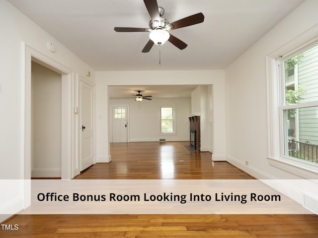 1410 Shawnee St, Durham, NC 27701 - unfurnished living room featuring wood finished floors, a ceiling fan, and a brick fireplace