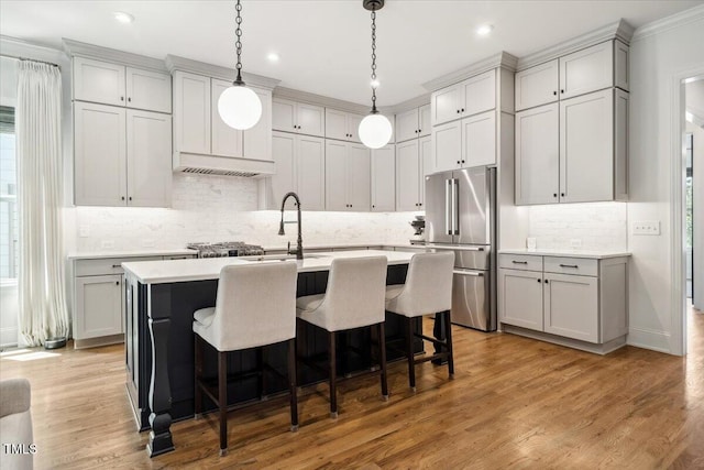 245 Tumbling River Dr, Wendell, NC 27591 - kitchen with freestanding refrigerator, light countertops, a center island with sink, decorative backsplash, and a breakfast bar