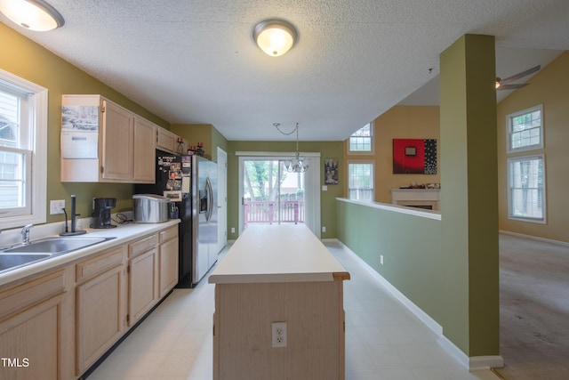 203 Halls Mill Dr, Cary, NC 27519 - kitchen featuring light brown cabinetry, a kitchen island, a textured ceiling, a sink, and hanging light fixtures