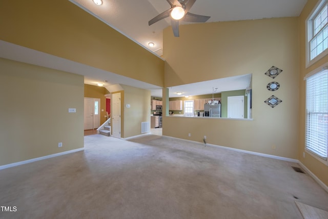 203 Halls Mill Dr, Cary, NC 27519 - unfurnished living room featuring a ceiling fan, baseboards, a towering ceiling, light colored carpet, and stairs