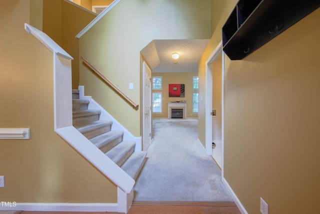 203 Halls Mill Dr, Cary, NC 27519 - carpeted foyer with stairs, a glass covered fireplace, and baseboards