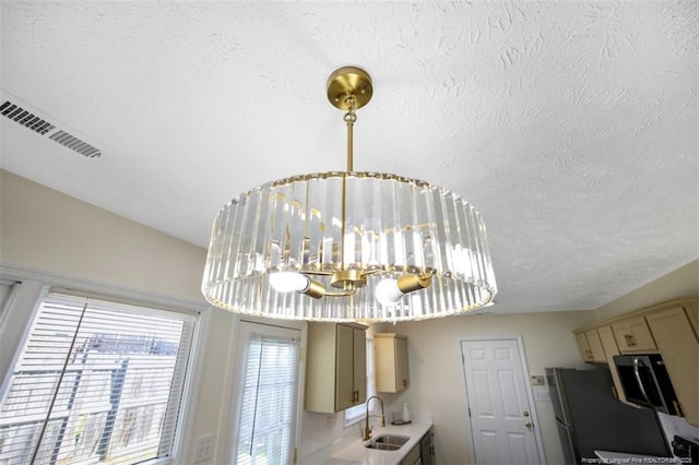 6466 Applewhite Rd, Fayetteville, NC 28304 - detailed view of a sink, a chandelier, freestanding refrigerator, a textured ceiling, and range