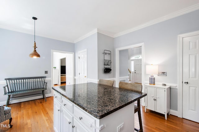3304 Buck Run Trl, Wake Forest, NC 27587 - kitchen with light wood-style flooring, white cabinets, ornamental molding, hanging light fixtures, and a kitchen breakfast bar