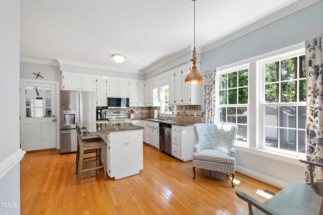 3304 Buck Run Trl, Wake Forest, NC 27587 - kitchen featuring appliances with stainless steel finishes, white cabinets, ornamental molding, a center island, and decorative backsplash