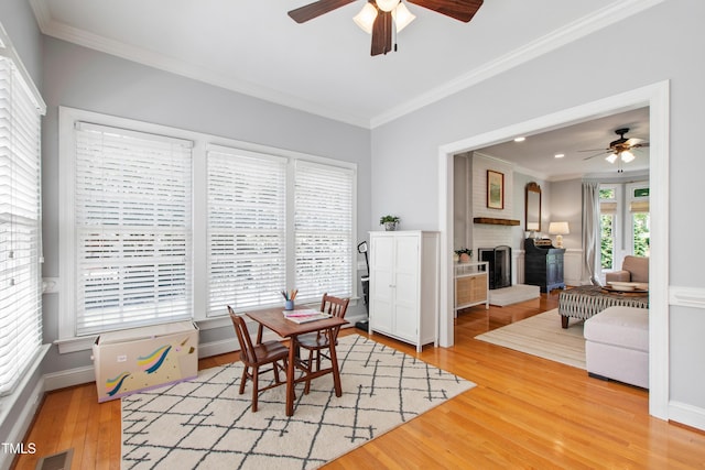 3304 Buck Run Trl, Wake Forest, NC 27587 - dining room with a ceiling fan, ornamental molding, a brick fireplace, and light wood-style floors