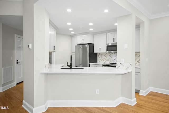 95113 Vance Knls, Chapel Hill, NC 27517 - kitchen featuring stainless steel appliances, a sink, light wood-style floors, decorative backsplash, and light countertops
