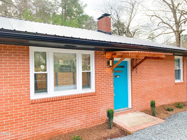 2907 University Dr, Durham, NC 27707 - view of exterior entry featuring brick siding, a metal roof, and a chimney