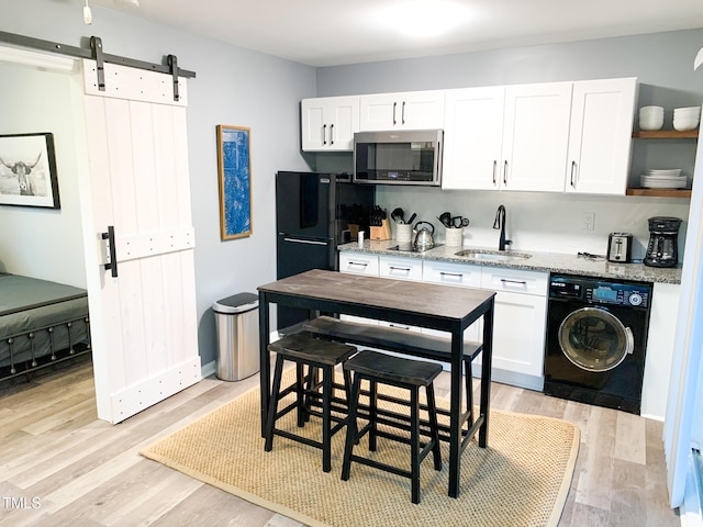 2907 University Dr, Durham, NC 27707 - kitchen with washer / clothes dryer, black appliances, white cabinets, and a barn door