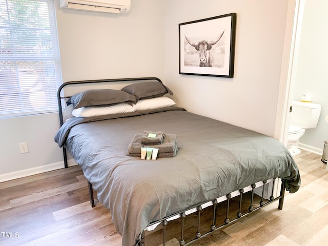 2907 University Dr, Durham, NC 27707 - bedroom featuring an AC wall unit, wood finished floors, and ensuite bath