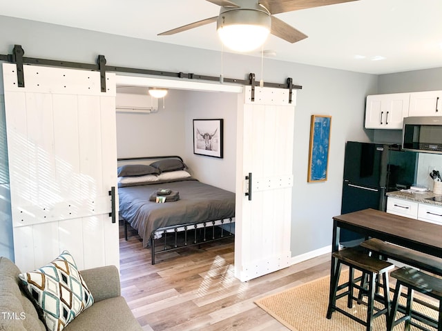 2907 University Dr, Durham, NC 27707 - bedroom with a barn door, freestanding refrigerator, light wood-style flooring, and a wall unit AC