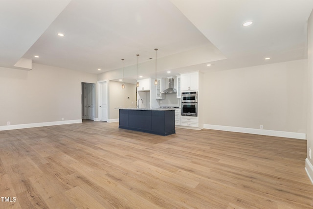 59 Cardinal Dr, Whispering Pines, NC 28327 - kitchen featuring wall chimney range hood, open floor plan, recessed lighting, baseboards, and light wood-style flooring