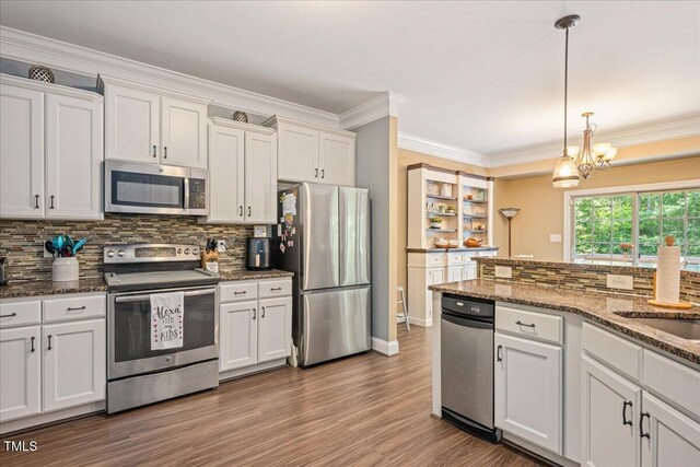110 Lexington Ave, Zebulon, NC 27597 - kitchen with appliances with stainless steel finishes, backsplash, white cabinetry, a chandelier, and pendant lighting