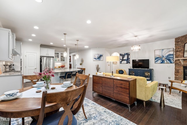1577 Tice Hurst Ln, Apex, NC 27502 - dining space with dark wood-type flooring, recessed lighting, a chandelier, and a fireplace
