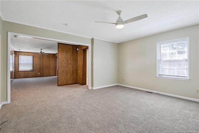 1486 Thelbert Dr, Fayetteville, NC 28301 - empty room featuring ceiling fan, light carpet, baseboards, crown molding, and wood walls