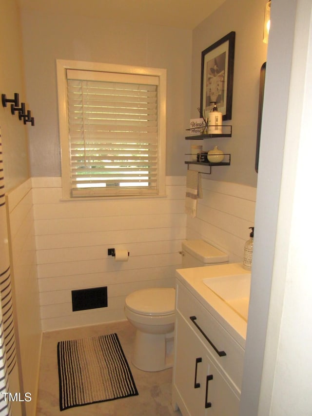 1700 Warrenton Rd, Henderson, NC 27537 - half bathroom featuring tile walls, vanity, toilet, a wainscoted wall, and tile patterned flooring