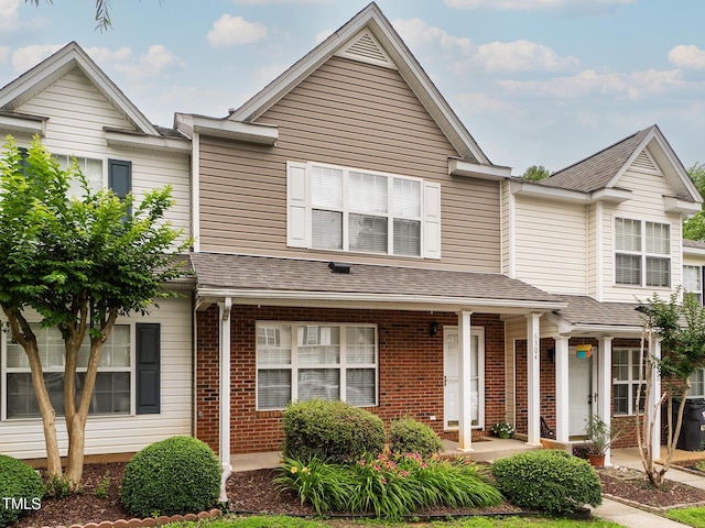 6304 Bermuda Way, Whitsett, NC 27377 - view of property with brick siding, a porch, and a shingled roof