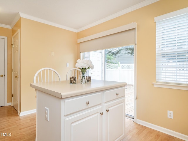 6304 Bermuda Way, Whitsett, NC 27377 - kitchen with light wood-style flooring, ornamental molding, white cabinetry, light countertops, and a center island