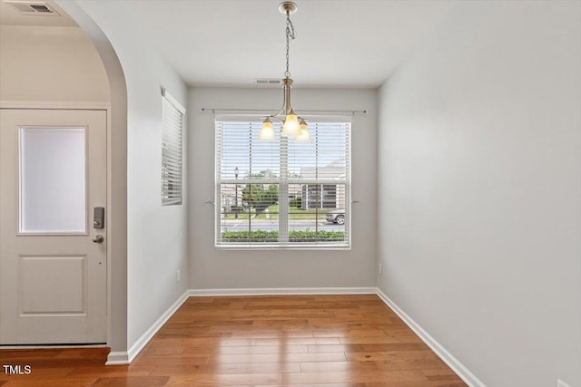 9327 Falkwood Rd, Raleigh, NC 27617 - unfurnished dining area with arched walkways, healthy amount of natural light, wood finished floors, and baseboards
