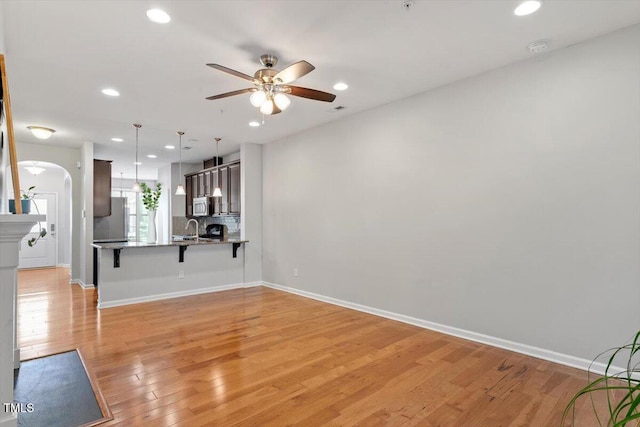 9327 Falkwood Rd, Raleigh, NC 27617 - unfurnished living room featuring a sink, a ceiling fan, arched walkways, recessed lighting, and light wood-type flooring