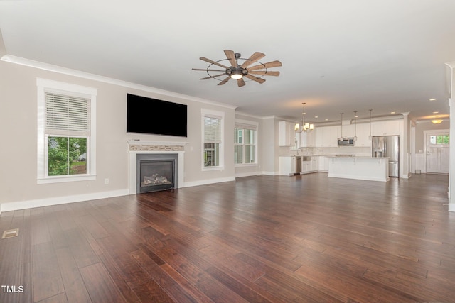 90 Starwood Dr, Garner, NC 27529 - unfurnished living room featuring a chandelier, ceiling fan, ornamental molding, a glass covered fireplace, and dark wood-style floors