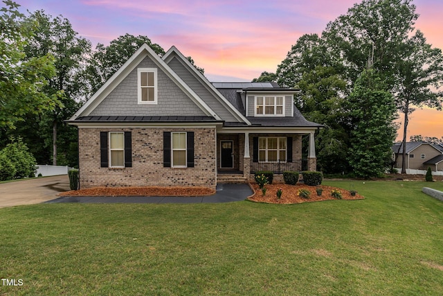 90 Starwood Dr, Garner, NC 27529 - craftsman house featuring brick siding, a porch, solar panels, a front lawn, and a standing seam roof