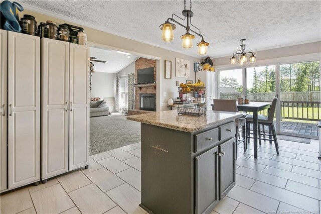 7578 Firethorn Dr, Fayetteville, NC 28311 - kitchen with light carpet, a brick fireplace, a center island, pendant lighting, and a textured ceiling