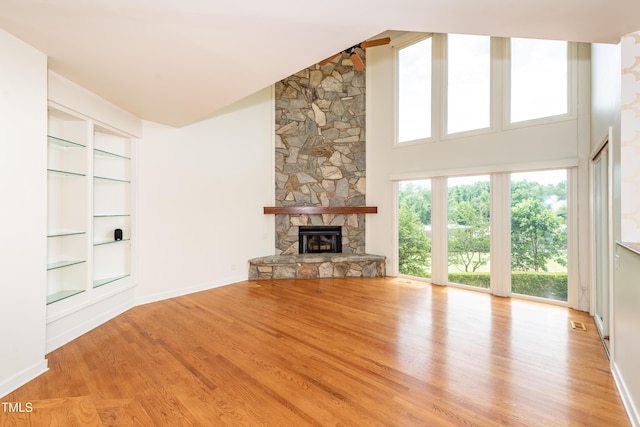 112 Lancaster Dr, Chapel Hill, NC 27517 - unfurnished living room featuring built in features, wood finished floors, a stone fireplace, baseboards, and a high ceiling