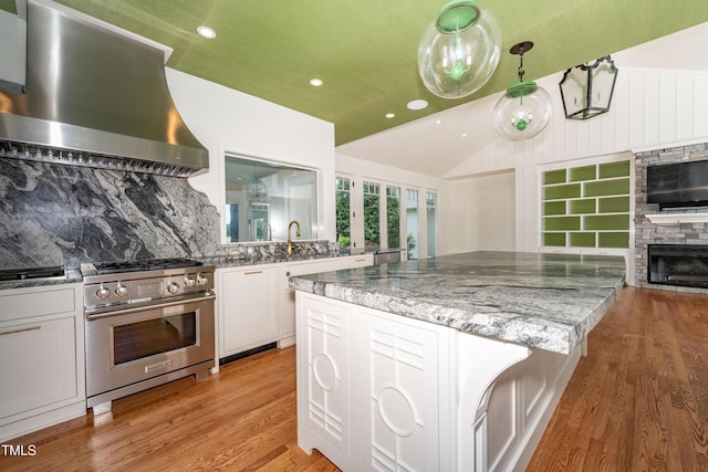 112 Lancaster Dr, Chapel Hill, NC 27517 - kitchen featuring stainless steel gas range oven, wall chimney range hood, lofted ceiling, light wood-type flooring, and light stone countertops