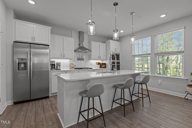 604 Craftsman Ridge Trl, Knightdale, NC 27545 - kitchen with appliances with stainless steel finishes, wall chimney exhaust hood, a sink, a center island with sink, and light countertops