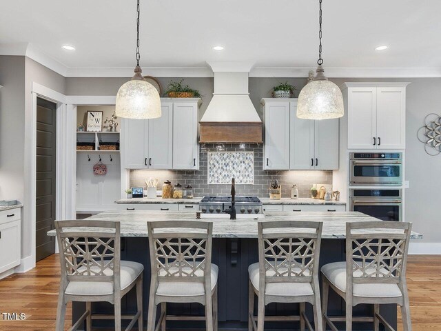67 Spring Hollow Ct, Pittsboro, NC 27312 - kitchen with custom range hood, light wood-style flooring, a kitchen bar, tasteful backsplash, and crown molding