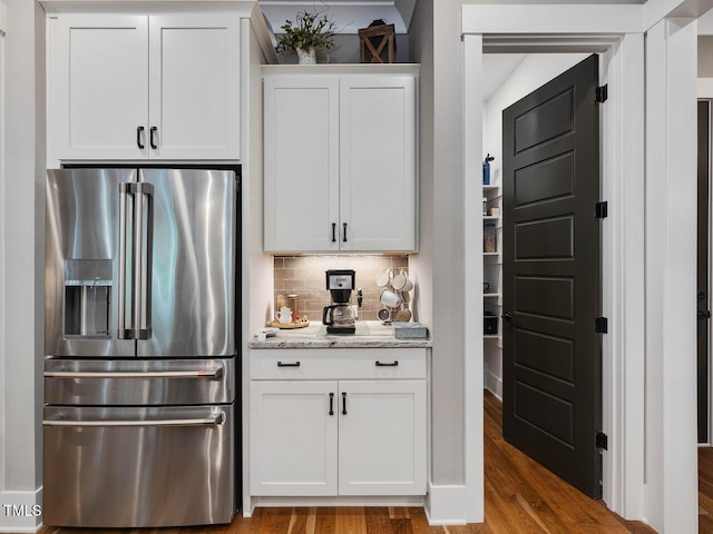 67 Spring Hollow Ct, Pittsboro, NC 27312 - kitchen with high quality fridge, wood finished floors, backsplash, white cabinetry, and light stone countertops