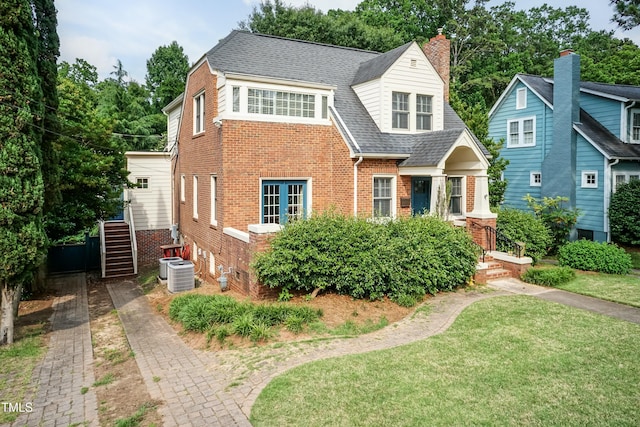 2236 The Cir, Raleigh, NC 27608 - view of front of house featuring brick siding, a front yard, central AC, roof with shingles, and a chimney