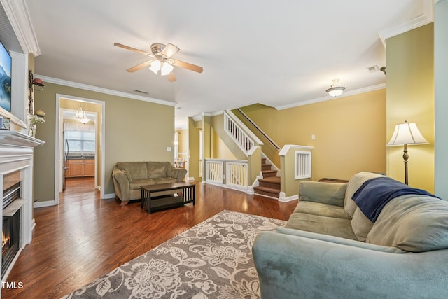 9808 Rainsong Dr, Wake Forest, NC 27587 - living area with a warm lit fireplace, a ceiling fan, stairs, wood finished floors, and crown molding