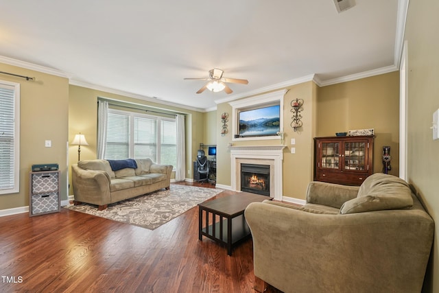 9808 Rainsong Dr, Wake Forest, NC 27587 - living room featuring ceiling fan, crown molding, baseboards, dark wood-style flooring, and a warm lit fireplace